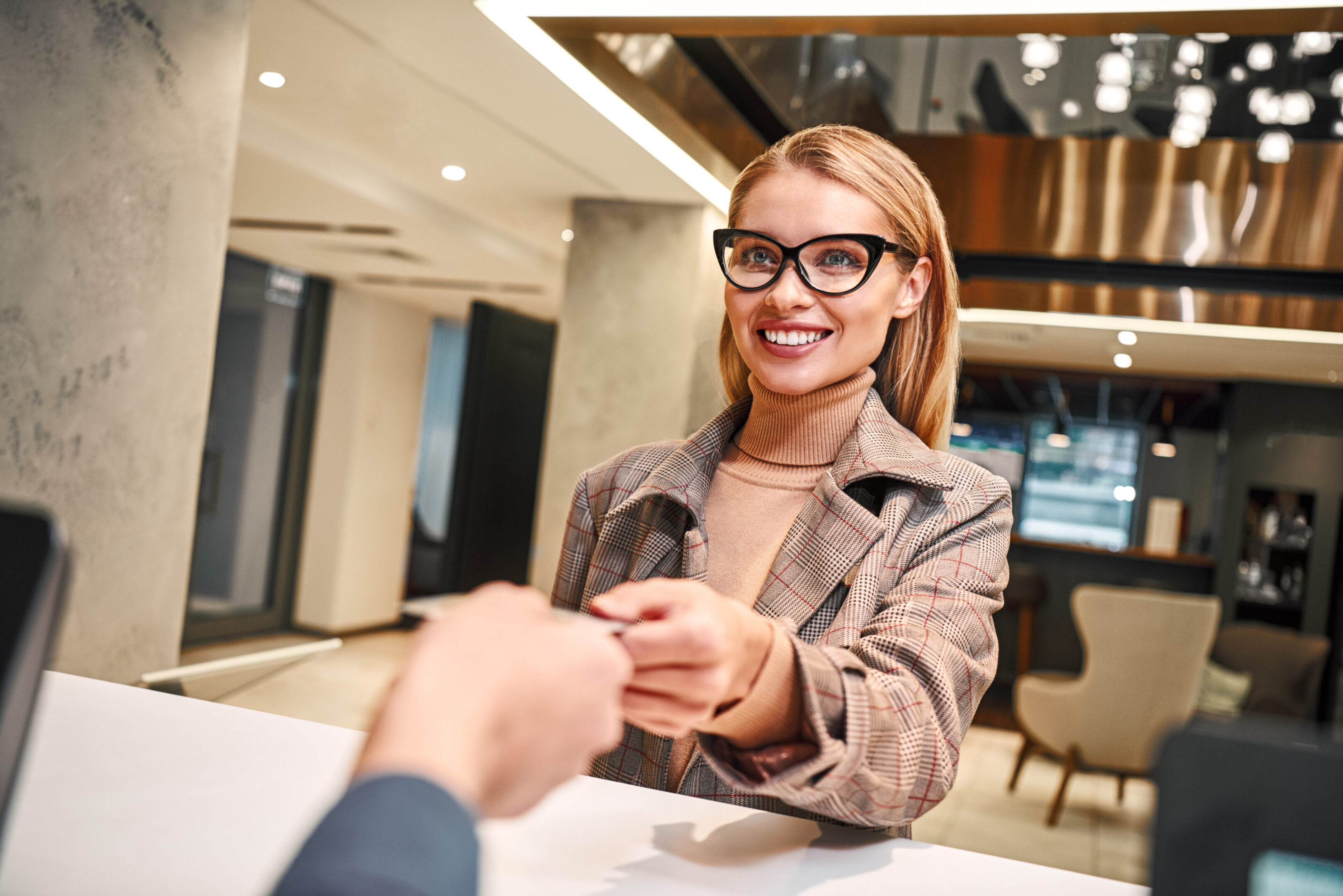 Check in hotel after long business trip. Close-up of woman in hotel check in at reception or front office being given key card.